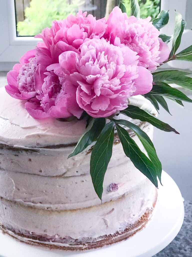 Piękny tort "naked cake" z&nbsp;pysznym kremem, owocami i&nbsp;świeżymi kwiatami.